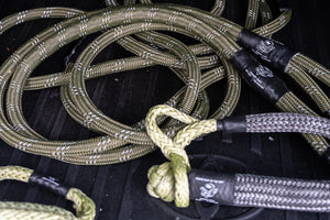 Close-up of olive green Kinetic-X kinetic recovery ropes and soft shackles on a truck bed, designed for heavy-duty off-road vehicle recovery.