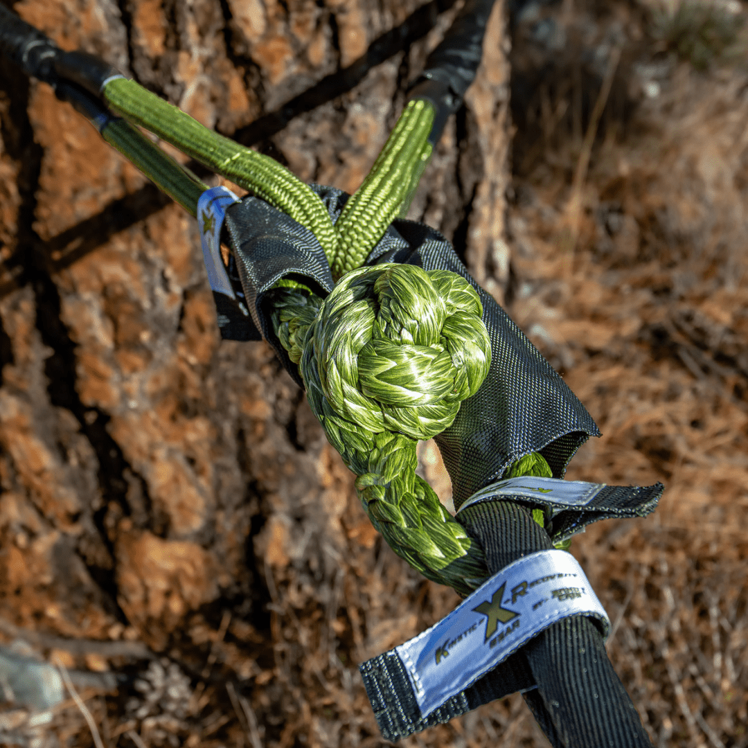 Green Kinetic-X soft shackle connected to a static bridle wrapped around a tree, demonstrating a secure and safe anchor setup for vehicle recovery.