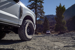 Two off-road vehicles using a winch line for recovery on a rocky mountain trail